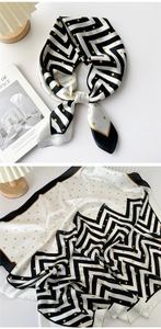 Close-up of a black and white geometric wave print silk scarf with golden polka dots