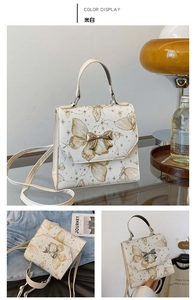 Detailed close-up of cream white handbag featuring golden butterfly prints and star patterns