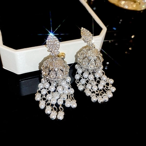 Macro des boucles d'oreilles jhumka argentées avec strass et glands de perles blanches