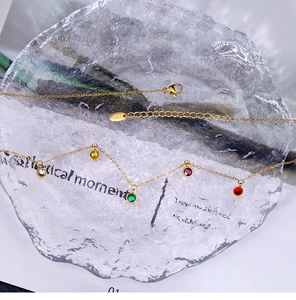 Detail of 18K gold plated anklet with five-color crystals on textured glass tray