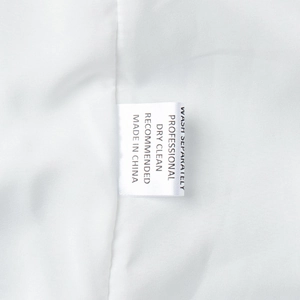 Detailed view of clothing care label showing wash instructions on white cotton fabric