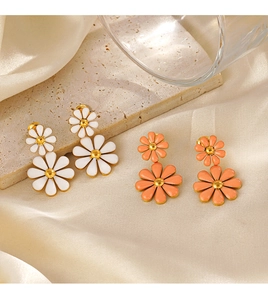 Detail view of double-layered daisy drop earrings with white and orange enamel petals