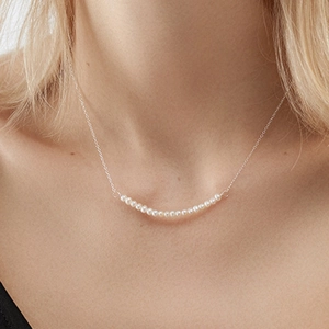 Close-up of minimalist freshwater pearl necklace worn on model neck and collarbone