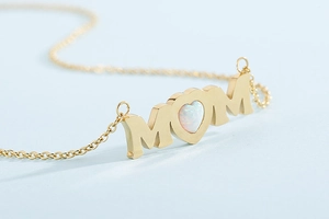 Macro shot of gold MOM pendant necklace with heart-shaped opal stone inlay details