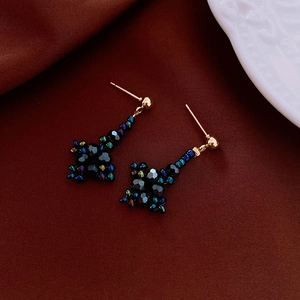 Détail des boucles d'oreilles faites main en perles noires avec des accents dorés