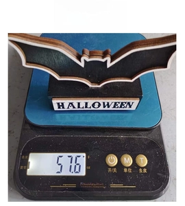 Macro shot of a wooden bat-shaped Halloween decoration weighing 57.6g on a digital scale