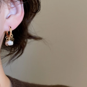 Detail of 18k gold plated tiger eye and pearl beaded hoop earrings worn by a model