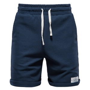 Detail of dark blue waffle knit shorts featuring elastic drawstring waist and hem tag