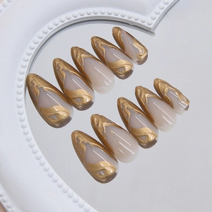 Golden sunset liquid metal marbling on nude almond press on nails on a mirrored tray