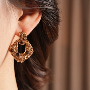 Gros plan de boucles d'oreilles vintage dorées avec strass ambrés sur un mannequin