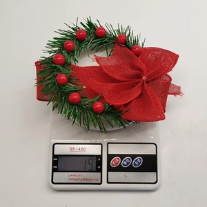 Detailed view of 19g mini Christmas wreath with red berries and bow on a scale
