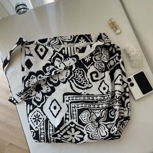 Detailed top view of a large bohemian crossbody bag with black and white floral prints