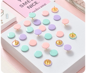 Macro view of pastel pink, green, and purple thumbtacks on a white display stand