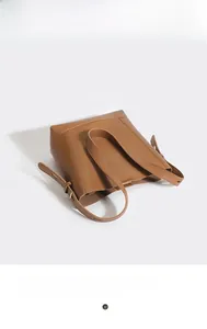 Detail view of large brown leather bucket bag with adjustable strap and wide handle