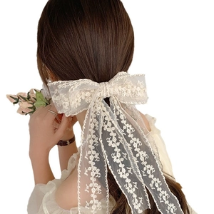 Romantic beige lace bow hair clip with floral embroidery and long ribbons on model