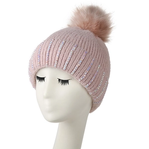 Pink knitted winter hat for women featuring a large faux fur pompom and sparkling rhinestones