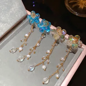Floral crystal beaded earrings with freshwater pearl tassels on pink jewelry box display