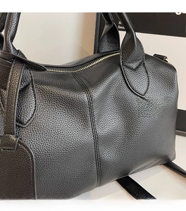 Close-up of black lychee grain leather texture and reinforced stitching on a tote bag