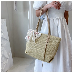 Detail of a woven straw tote bag with delicate floral embroidery ribbon and strap
