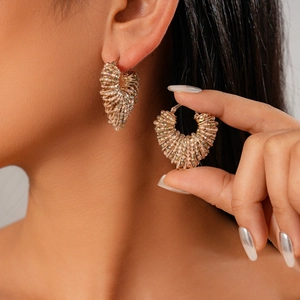Rainbow beaded heart-shaped earrings with gold metal hoops shown on model
