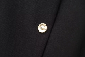 Vue macro d'un bouton métallique doré sur un tissu de vêtement noir tissé de luxe