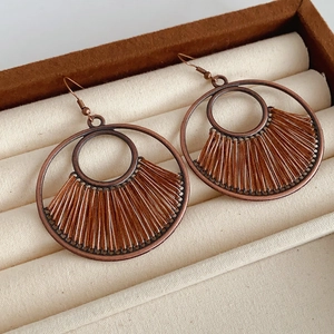 Detailed macro view of vintage bronze-tone earrings with brown woven bohemian pattern