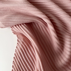 Detailed macro view of pink pleated fabric with distinctive striped texture and soft shadow