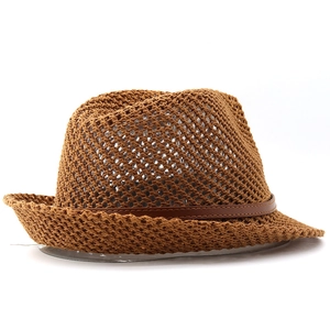 Detailed view of breathable crochet pattern and brown faux leather band on straw hat