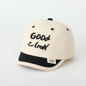 Close-up of beige baseball cap with black Good Luck embroidery and smiley face detail