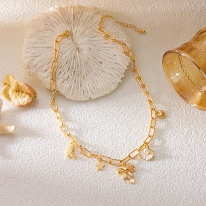 Detailed shot of golden multi-charm necklace with seashell, heart, and star pendants