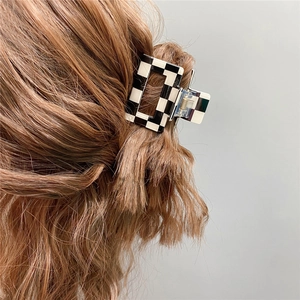 Side view of a large black and white checkered hair claw clip worn by a model