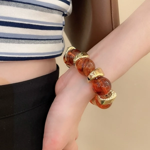 Detail of amber acrylic beads and textured gold metal accents on a stylish bracelet