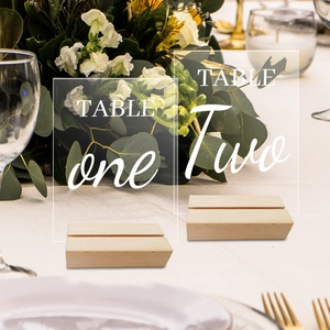 Close-up of clear acrylic table numbers with wooden stands for elegant wedding decor