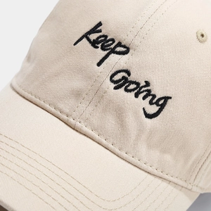 Beige cotton baseball cap with black Keep Going embroidery and detailed stitching