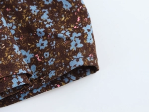 Close-up of floral chiffon fabric showing blue and pink flowers on dark brown background