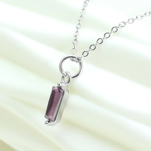 Close-up of a silver necklace featuring a rectangular purple zircon gemstone pendant