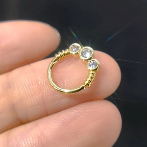 Macro view of gold septum ring with micro-pave zircons and wire wrapping details