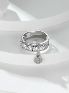 Detail shot of a silver S925 ring with cubic zirconia inlay and a round charm on silk