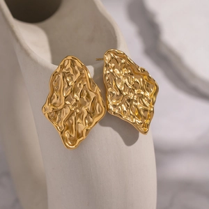 Detailed macro view of 18K gold plated earrings with hammered texture and geometric shape