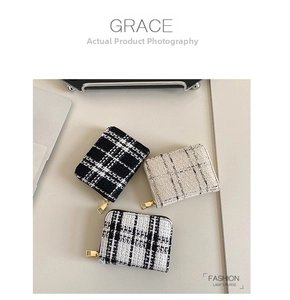 Three tweed checkered women's wallets with golden zippers displayed on a beige tabletop