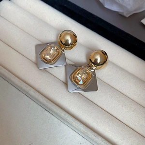 Gros plan de boucles d'oreilles géométriques avec cristal champagne dans un écrin
