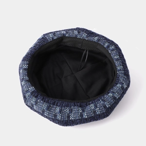 Blue tweed beret hat with interior lining and adjustable drawstring detail on white background