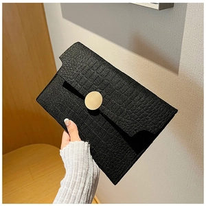 Close-up of black crocodile-embossed envelope clutch with a gold circular buckle