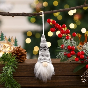 Detail of Christmas gnome ornament with knitted hat and plush beard on a festive branch
