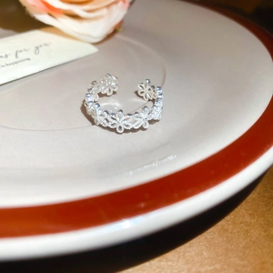 Close-up of silver hollow floral lace ring on decorative ceramic plate with soft floral background