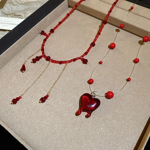 Detail of red crystal beaded necklaces with lava heart pendant and gold tassels