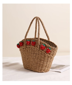 Close-up of woven straw handbag featuring cute red strawberry accents on a white surface