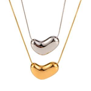 Detail of high-polish heart bean pendants in gold and silver on sleek snake chains