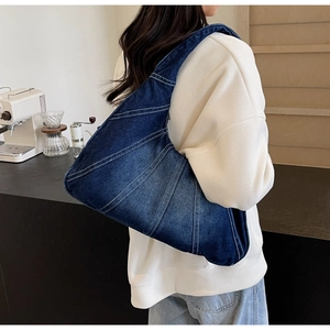 Détail du sac à bandoulière en denim bleu avec surpiqûres blanches et large sangle