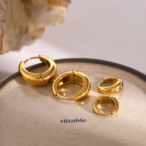 Set of four 18k gold plated stainless steel hoop earrings in various sizes on a ceramic tray